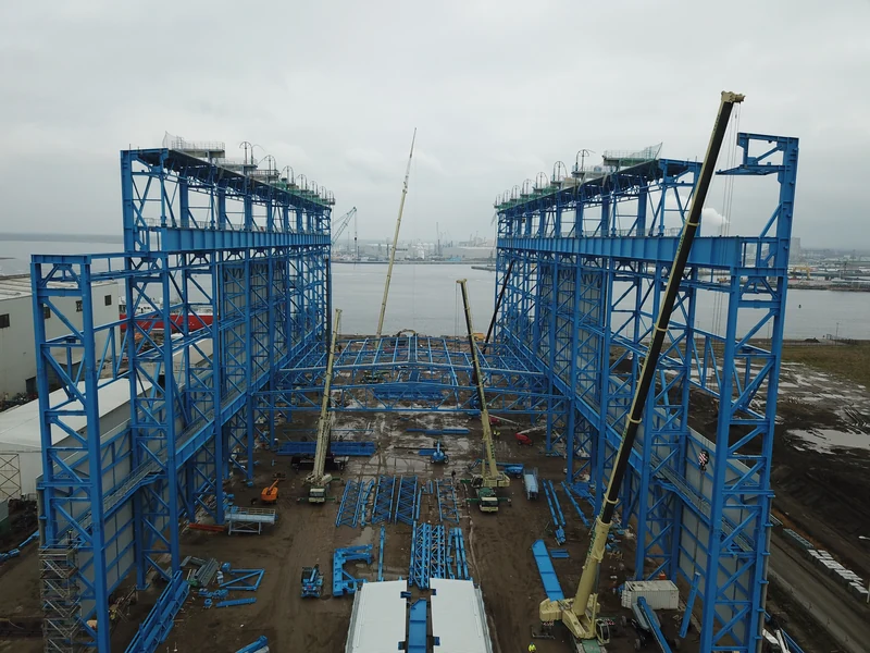Blaue Stahlkonstruktion der Neptun Werft während der Montage mit Kranen am Wasser